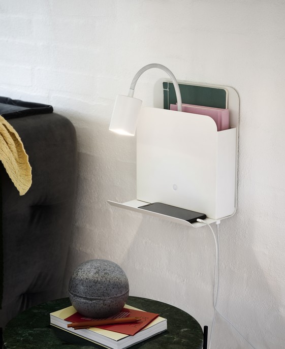 Multifunkční nástěnná lampička Roomi od Nordluxu s přihládkou na časopisy, poličkou na odkládání věcí, s USB vstupem pro dobíjení a nastavitelným ramenem pro přesné nasměrování světelného paprsku. Dostupná v černé a bílé variantě.